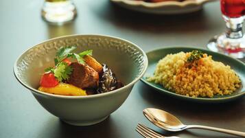 A bowl of stew with vegetables and a side of couscous on a table.