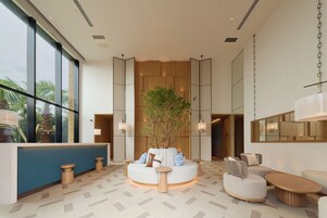 Un vestíbulo moderno con una zona de estar central, ventanas amplias y una planta.