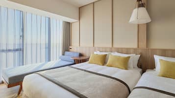 A hotel room with a large bed, a smaller sofa, a desk, and a window with curtains.