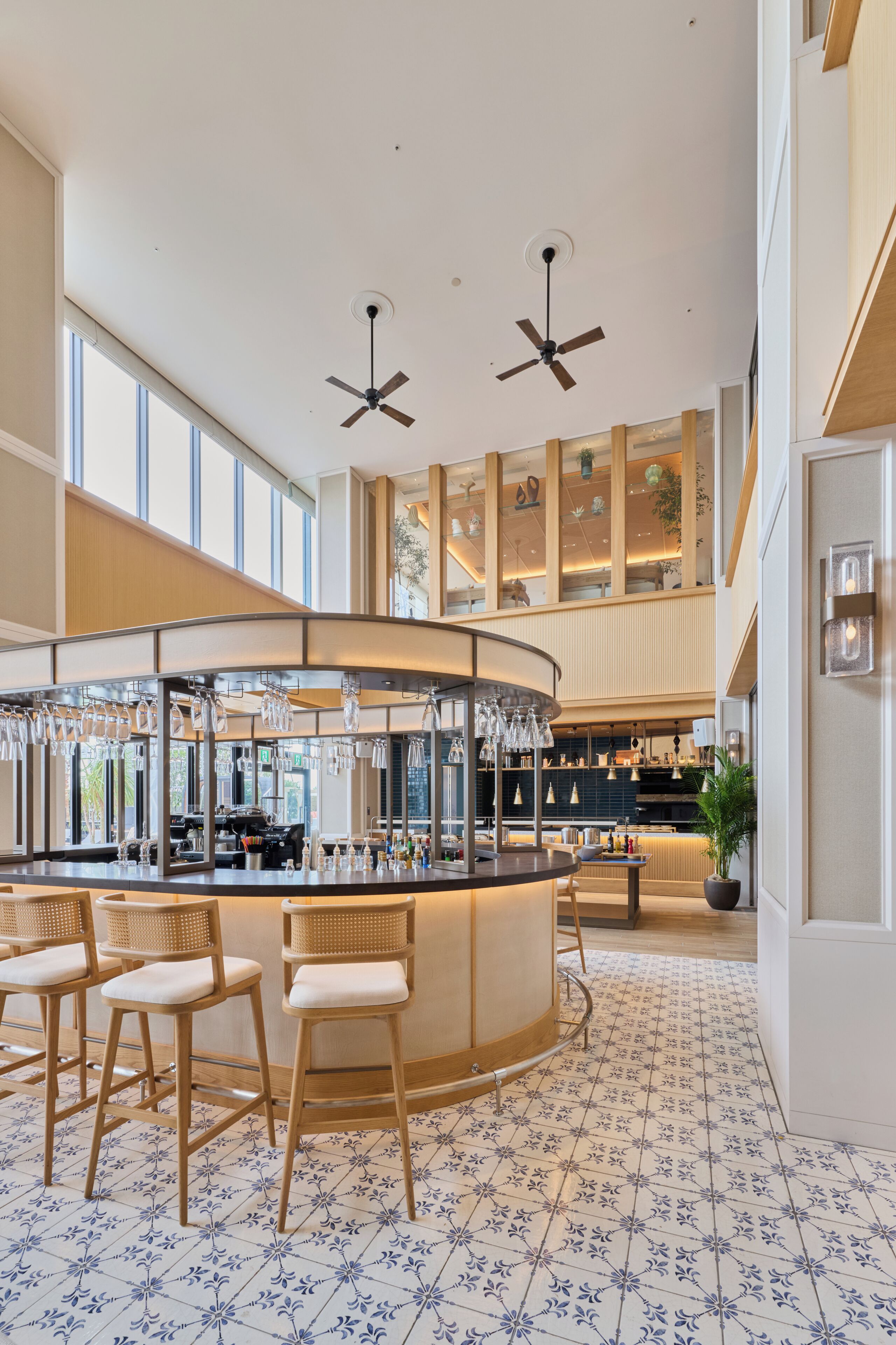 Un área de bar moderna con una barra curva, taburetes y ventiladores de techo.