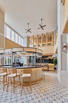 A modern bar area with a curved counter, bar stools, and ceiling fans.