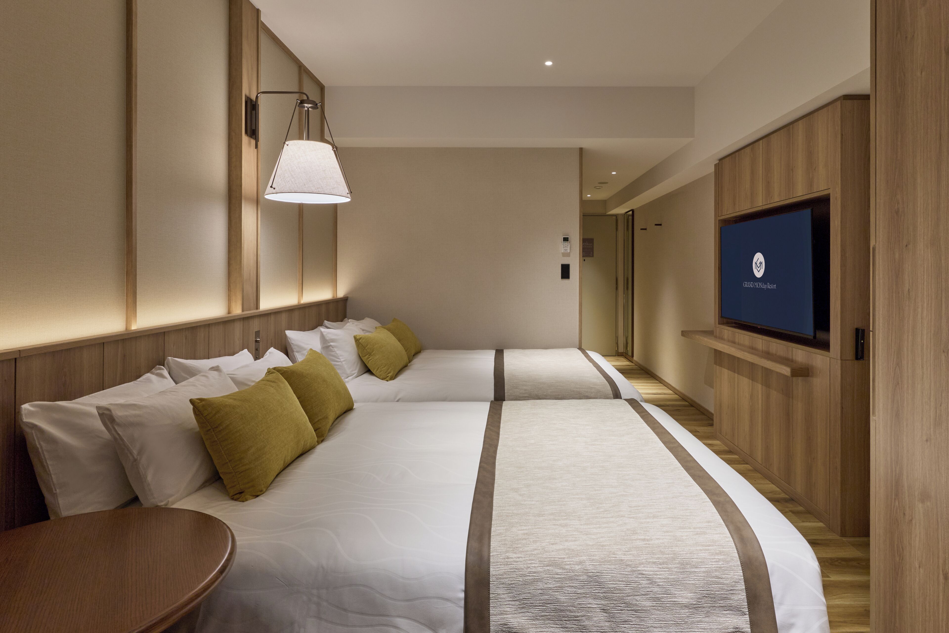 A hotel room with two beds, a TV, and a wooden panel wall.