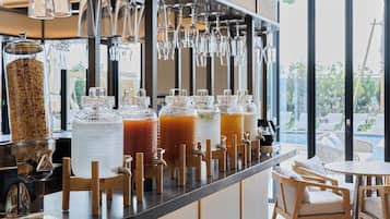 A bar area with multiple drink dispensers, a selection of glasses, and a view of the outdoors.