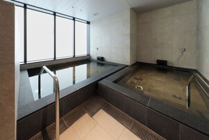 A modern indoor pool area with a glass floor, metal railings, and tiled walls.