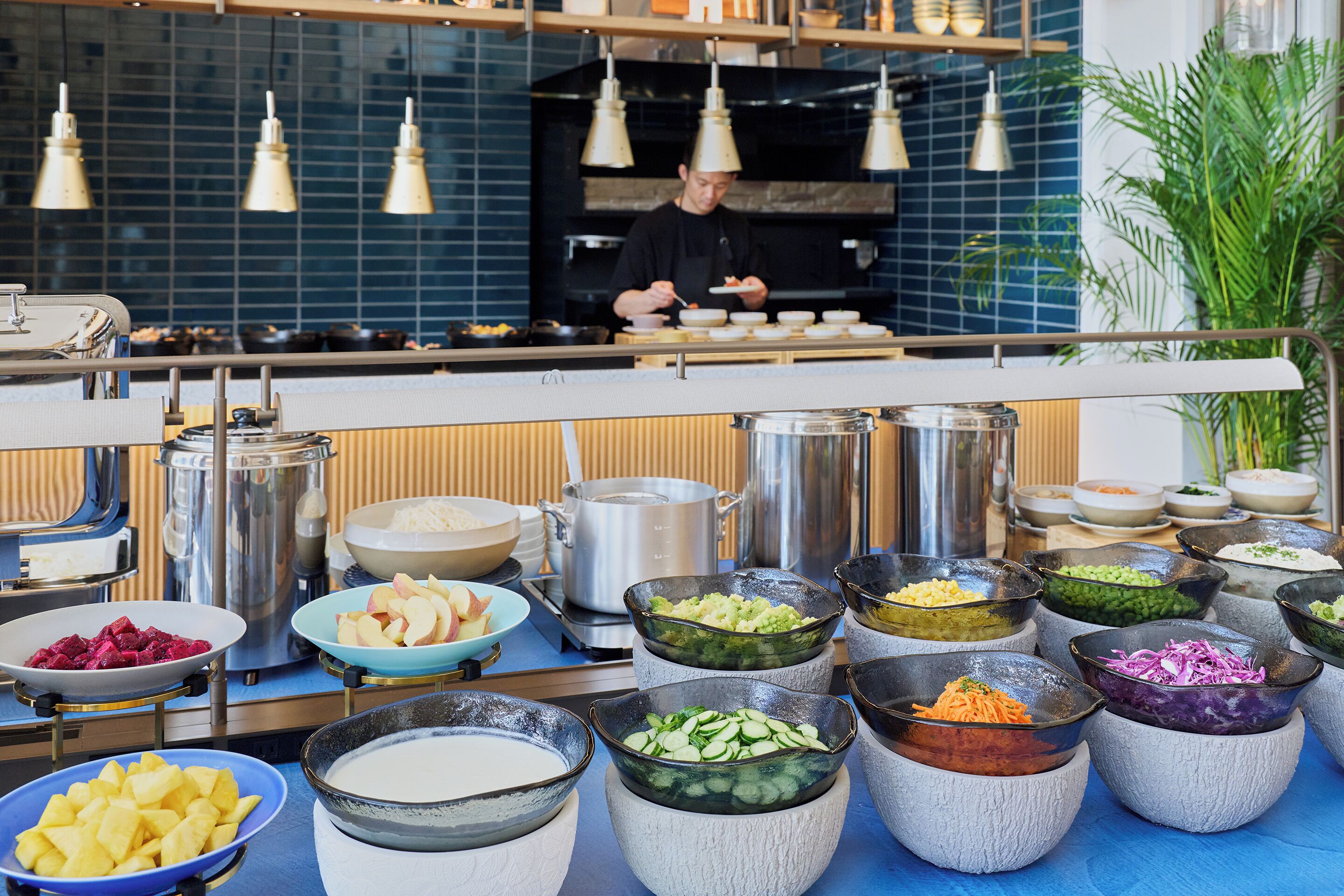 A buffet setup with various food items and cooking equipment.
