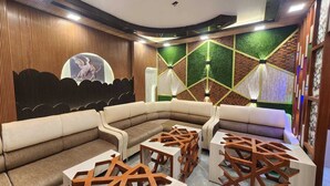 Un espace de détente moderne, avec un canapé incurvé, des tables en bois et un mur décoratif orné de motifs géométriques.