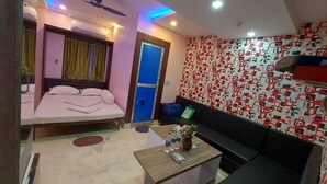 Une chambre d’hôtel avec un lit, un bureau, un canapé, un mur à motifs et une porte bleue.