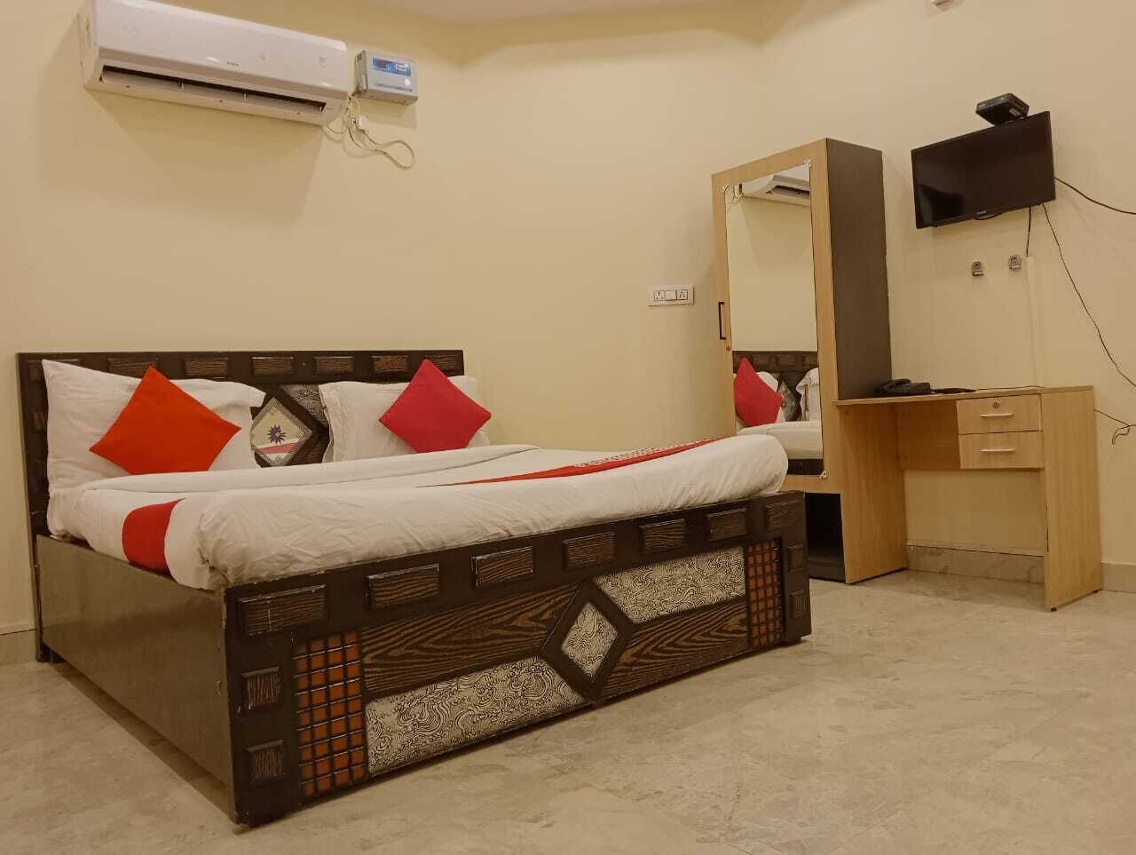 Quarto com cama, escrivaninha de madeira, espelho e ar condicionado.