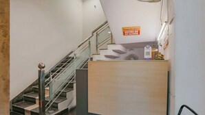 A reception desk with a sign indicating it is a private residence. A staircase with a metal railing is visible to the left. - Raj Residency Govindpuri (New Delhi)