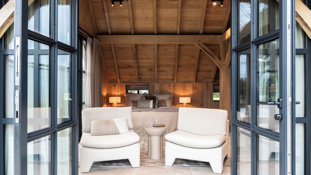 A room with two white sofas, a small round table, and a wooden ceiling. - Detached wellness cottage with private heated pool (Kortehemmen)