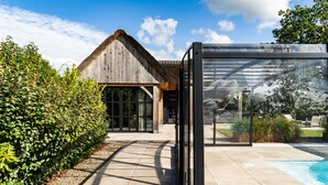 A modern house with a glass greenhouse, a swimming pool, and a well-maintained garden. - Detached wellness cottage with private heated pool (Kortehemmen)