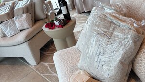 A hotel room with a sofa, a small table with a bottle, glasses, and a rose arrangement. - Detached wellness cottage with private heated pool (Kortehemmen)