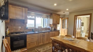 Una cocina con armarios de madera, una isla central y un comedor con sillas.