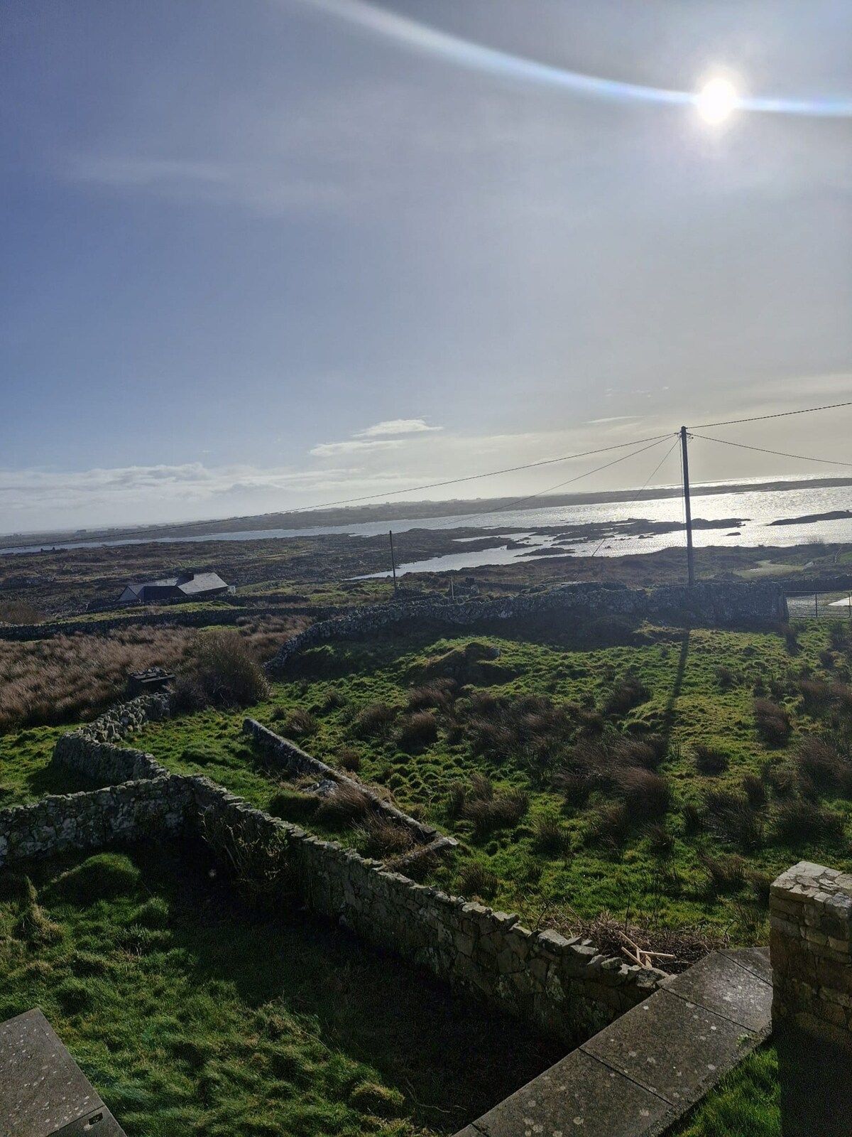 A coastal landscape with stone walls and a clear view of the sea.