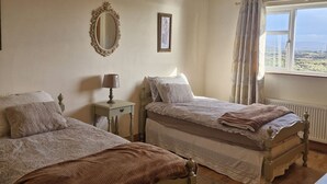 Un dormitorio con dos camas, un espejo, una lámpara, una ventana con cortinas y vistas al paisaje.