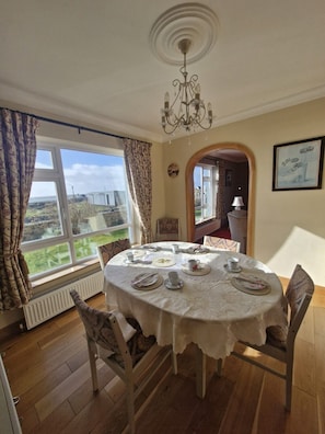 A dining room with a table set for four, a chandelier, and a view of the outdoors. - Teach na hAirde (Carna)