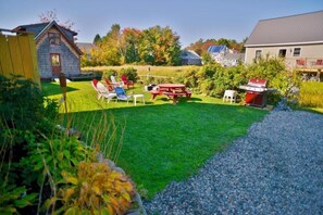 Ein Garten mit Picknicktisch, Stühlen und Grill.