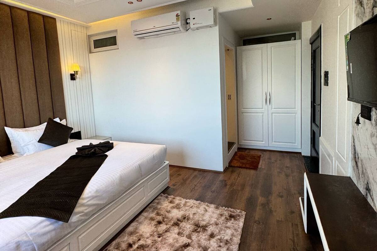 Quarto de hotel moderno com uma cama grande, um tapete macio, uma televisão e um guarda-roupa.
