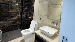 A modern bathroom with a toilet, sink, and shower. - HOTEL LA SERA (Srinagar)