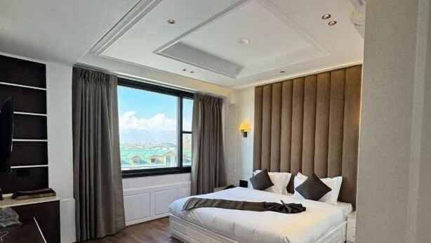 A modern hotel room with a large bed, a flat-screen TV, a view of the city, and a large window. - HOTEL LA SERA (Srinagar)