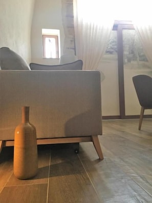 Une pièce avec un canapé, un vase en bois et une vue par la fenêtre.