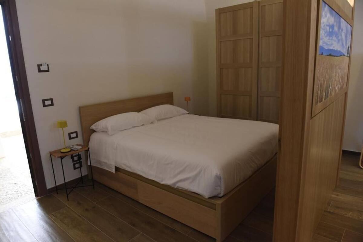 A single bed with a wooden headboard and a nightstand with a lamp.