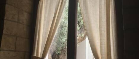 A window with a decorative metal frame and sheer curtains.