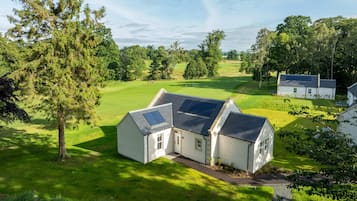 Una casa con paneles solares, un césped y un campo de golf al fondo.