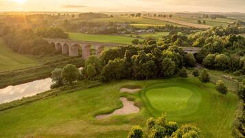 A golf course with a bridge, water body, and surrounding greenery.