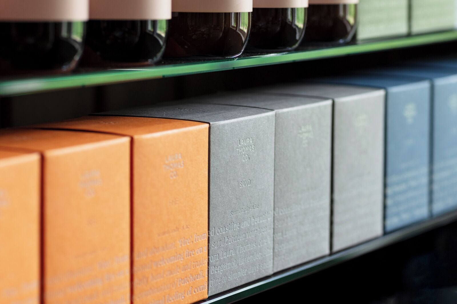 Une rangée de boîtes soigneusement alignées sur une étagère, chacune étant étiquetée avec un nom et une description du parfum.