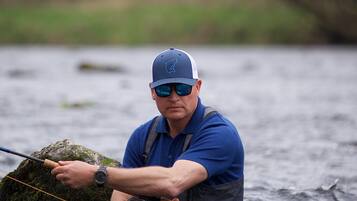 Una persona de pie en el agua, sosteniendo una caña de pescar.
