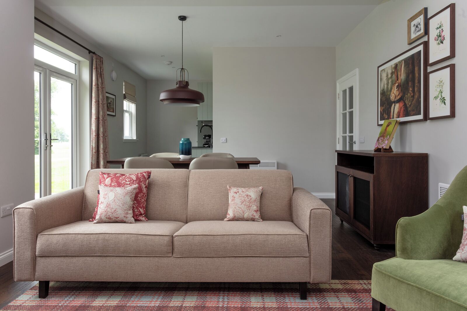 Una sala de estar con un sofá color beige, un sillón verde y una alfombra estampada.