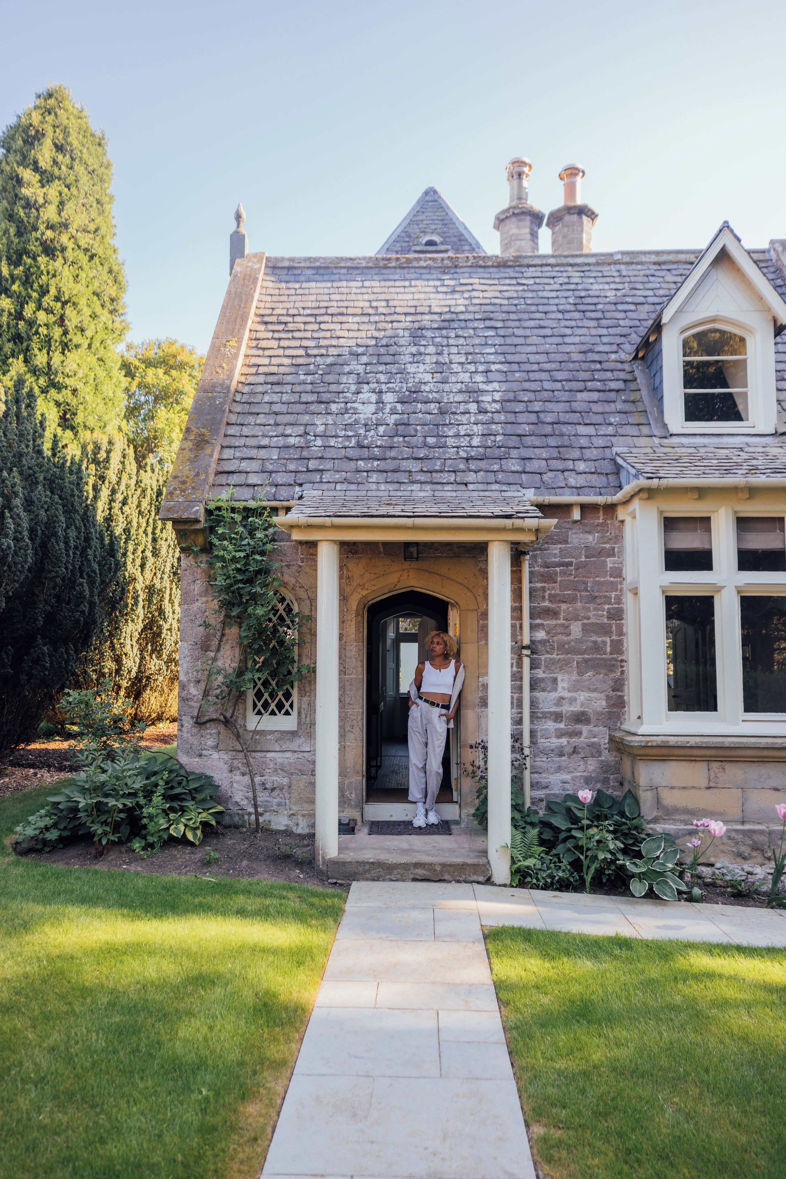 A stone house with a brick roof, a front door, and a pathway leading to the entrance.