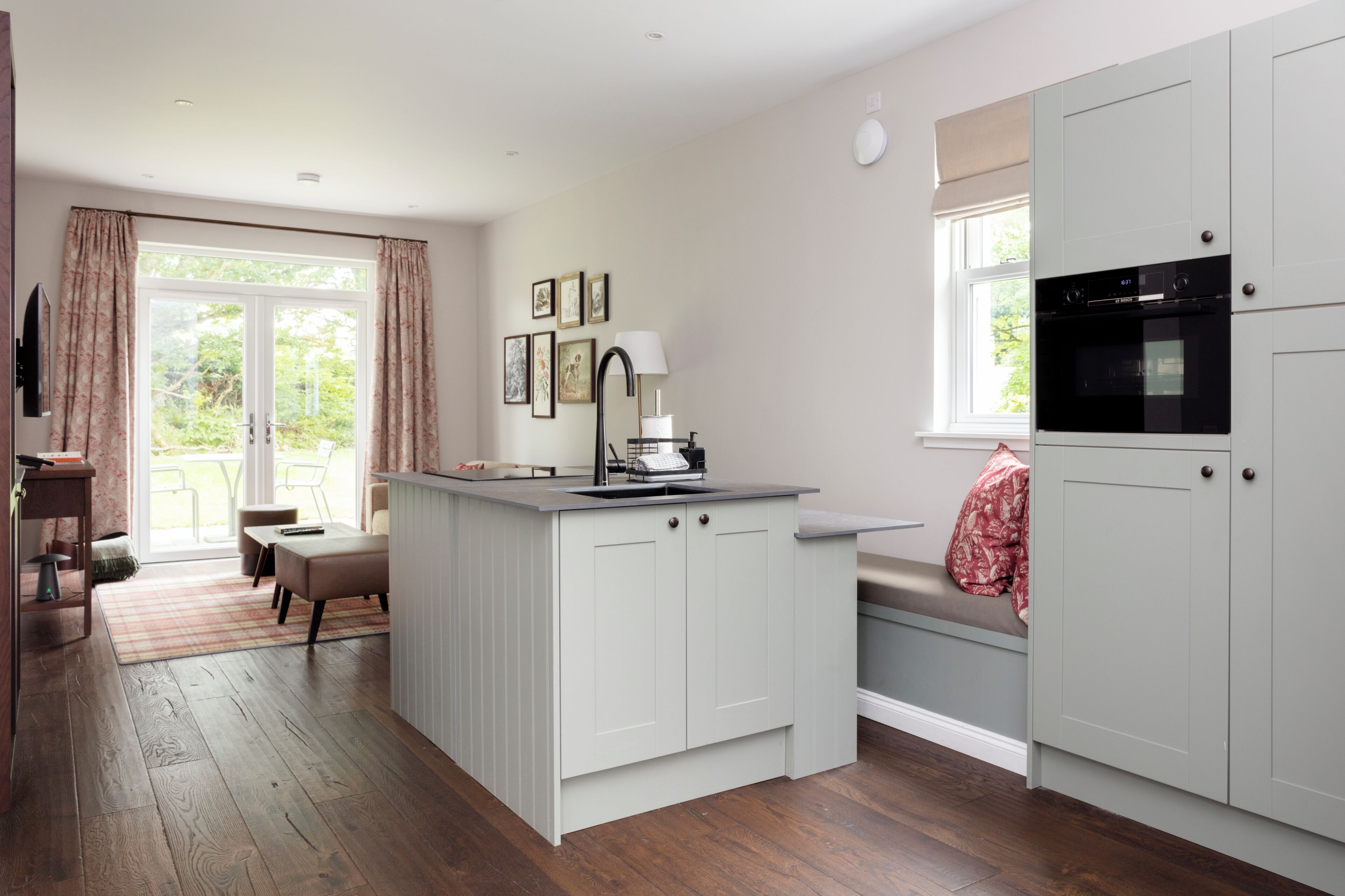 A kitchen with a central island, a dining area with a bench, and a window with curtains.