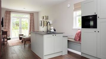 A kitchen with a central island, a dining area with a bench, and a window with curtains.