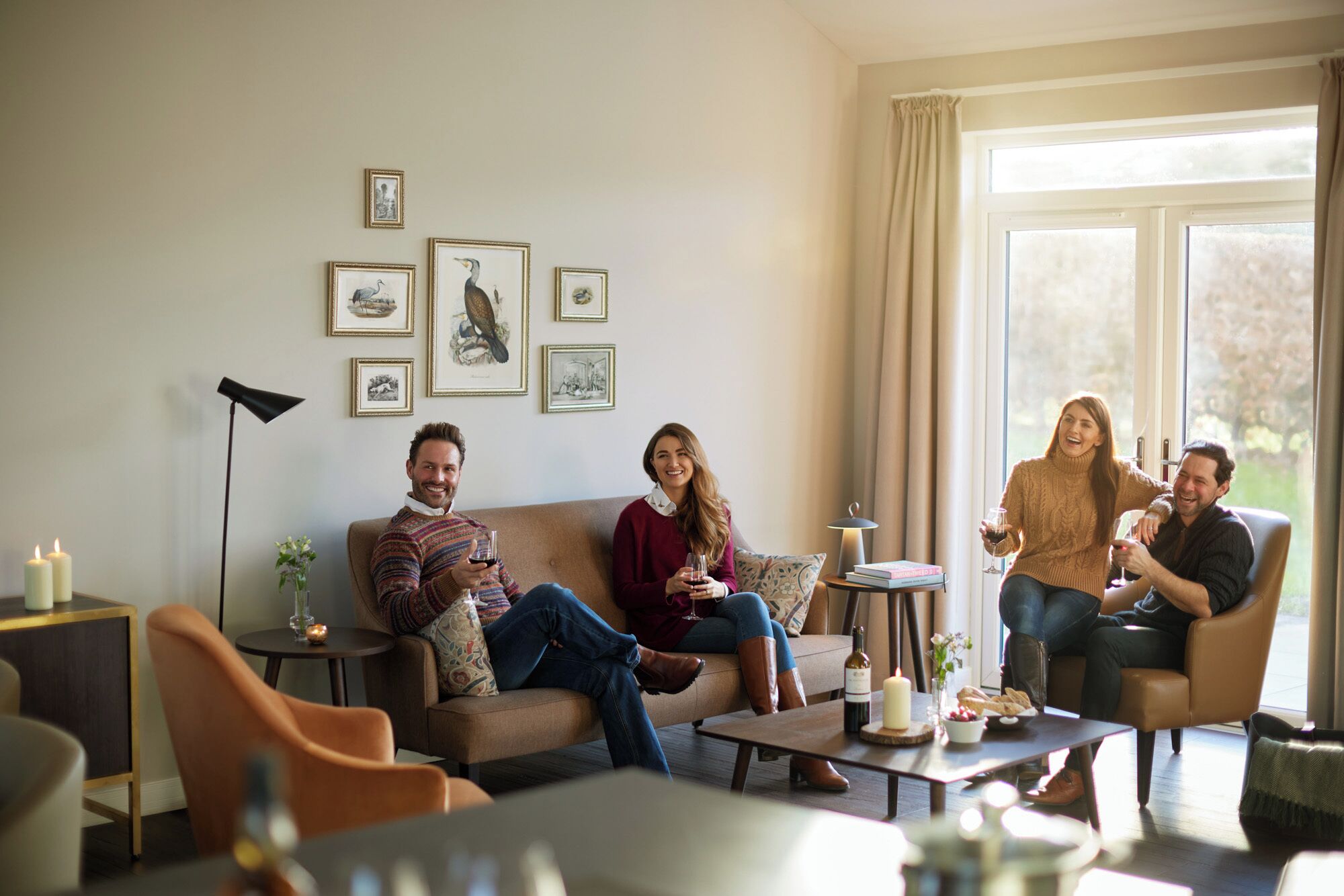 Ein Wohnzimmer mit einer Couch, Sesseln, einem Couchtisch und gerahmten Bildern an der Wand.