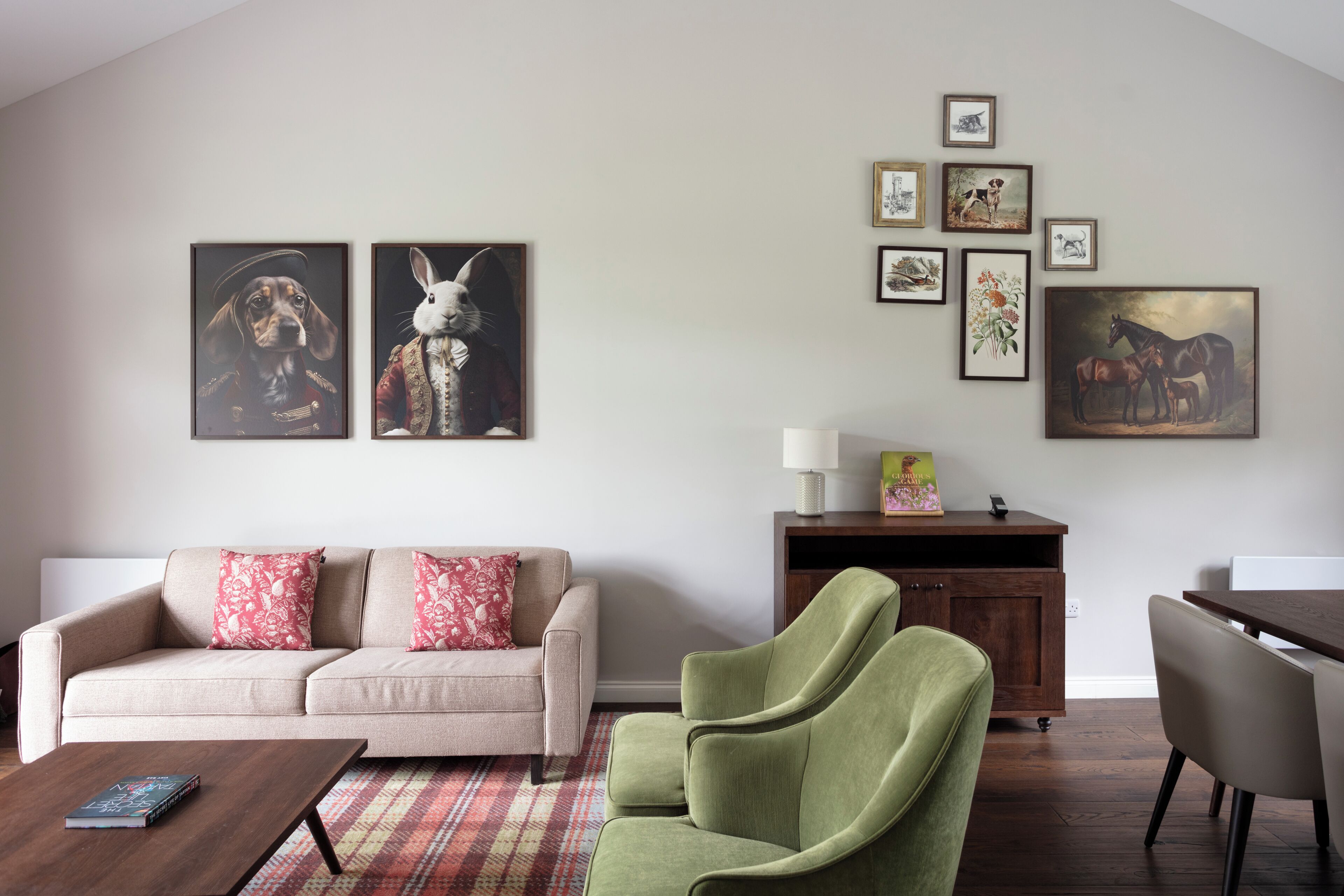 Een woonkamer met een bank, fauteuils, een salontafel en een eettafel. Er hangen ingelijste foto’s aan de muur.