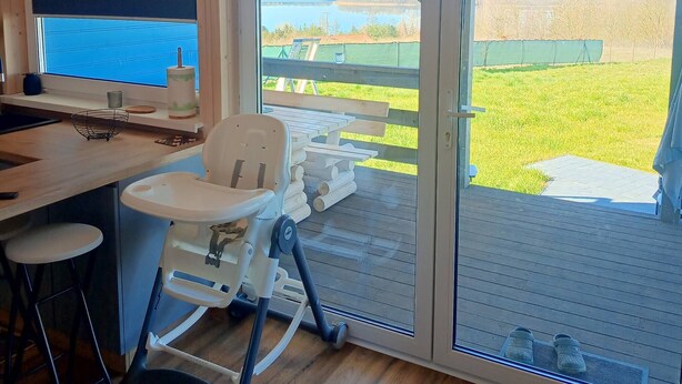 A room with a large window, a television, a baby changing station, and a wooden floor. - Domek nr 3 "błękitne Wzgórze" (gmina Brzuze)