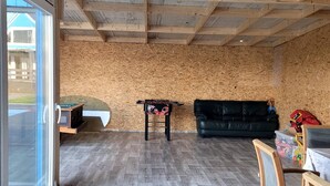 A room with a wooden ceiling, a black leather sofa, a wooden table, and a glass door leading outside. - Domek nr 3 "błękitne Wzgórze" (gmina Brzuze)