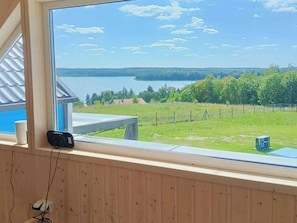 Ein Zimmer mit großem Fenster und Seeblick, einer Holzwand und einem kleinen Tisch.