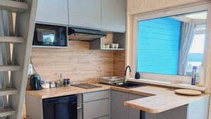 A compact kitchen with a dishwasher, a sink, and a window with a view. - Domek nr 3 "błękitne Wzgórze" (gmina Brzuze)