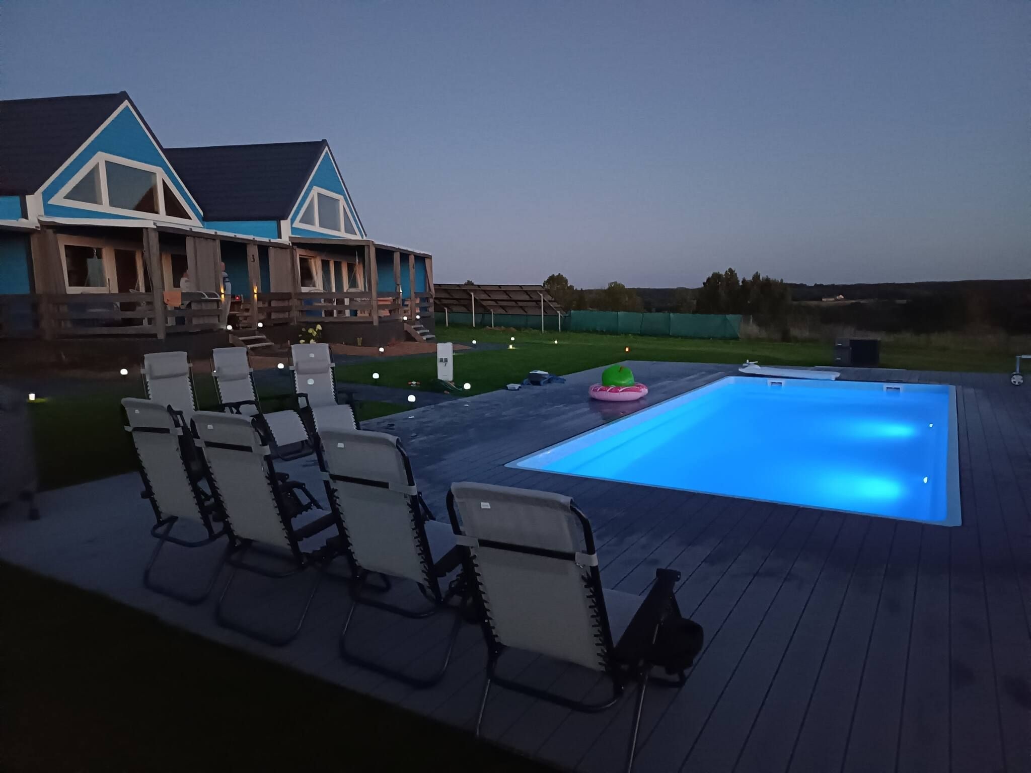 Une piscine avec des chaises longues et une maison en arrière-plan.