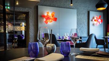 Interior de restaurante con una mesa lista para comer, con un menú, copas de vino y una pared decorativa.