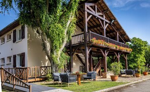 A building with a balcony, outdoor seating, and a staircase. - Hôtel Restaurant La Chaumière (Dole)