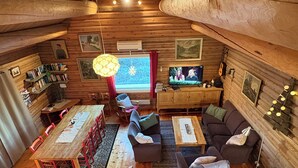 Ein gemütliches Blockhaus-Interieur mit Essbereich, Sofa, Fernseher und Bücherregalen.