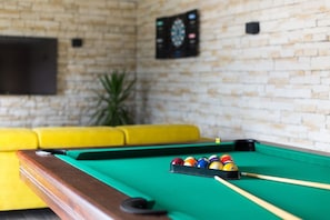 A pool table with balls and cues, a yellow sofa, and a brick wall. - Stylish vacation apartment in Crikvenica with pool (Crikvenica)