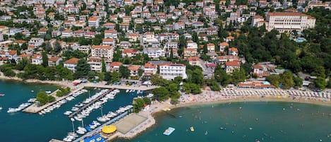 Luftaufnahme einer Küstenstadt mit Hafen, Strand und Wohnhäusern.