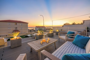 A rooftop terrace with outdoor seating, a table with drinks, and a sunset view. - Stylish vacation apartment in Crikvenica with pool (Crikvenica)