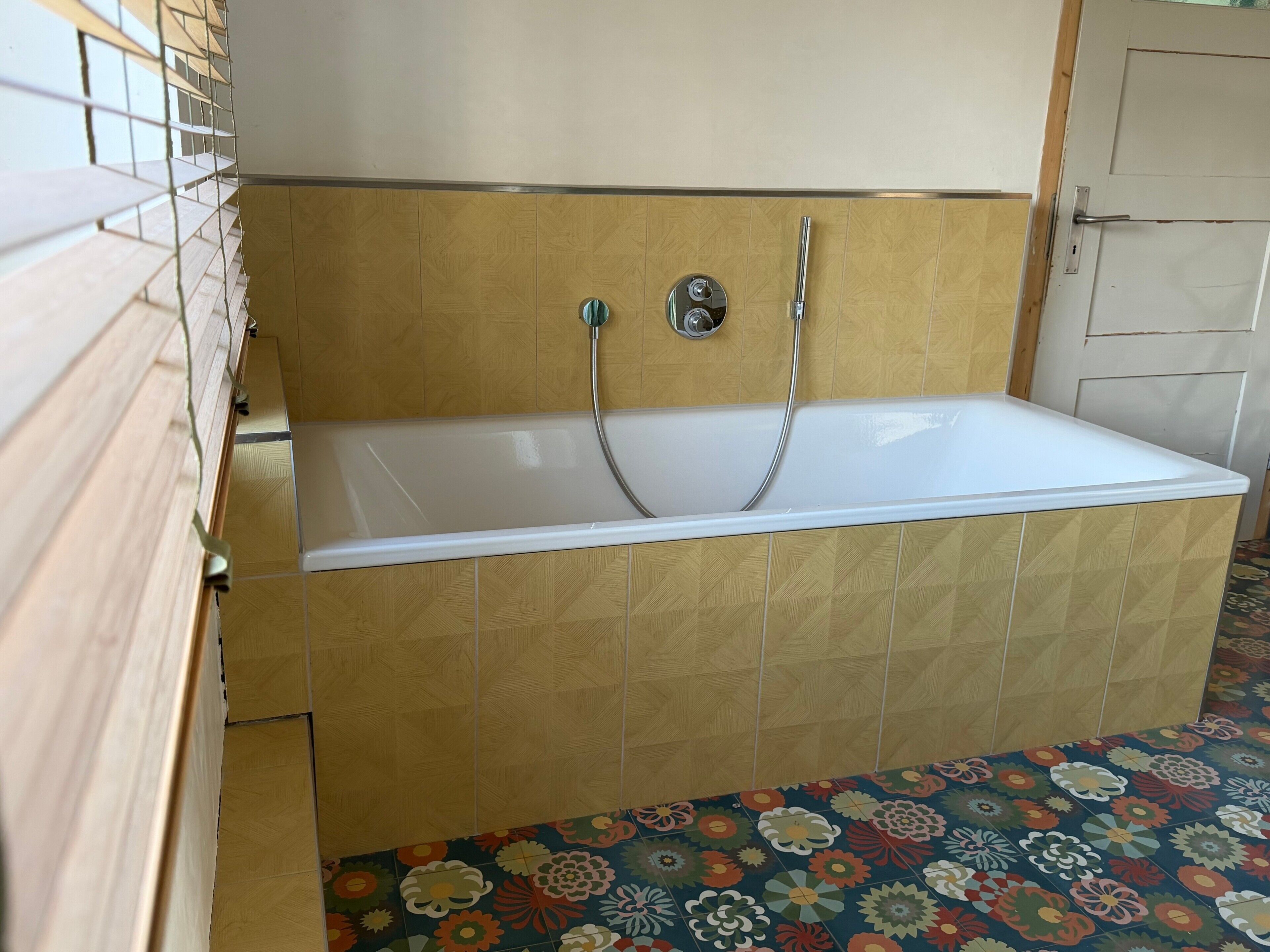 Une salle de bain avec une baignoire, un lambris en bois et des carreaux de sol à motifs.