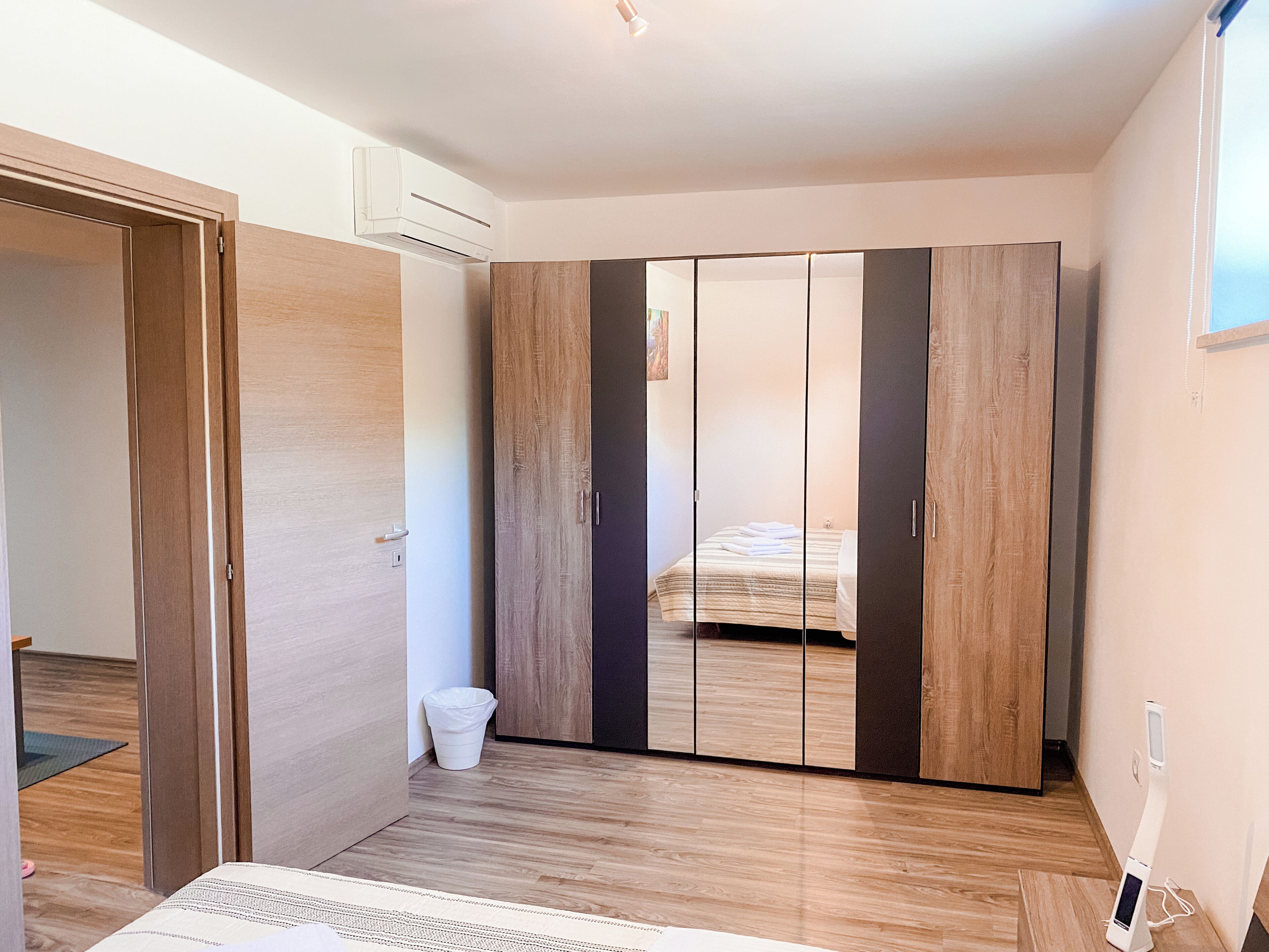 Ein Schlafzimmer mit Kleiderschrank, Bett und einem kleinen Mülleimer.